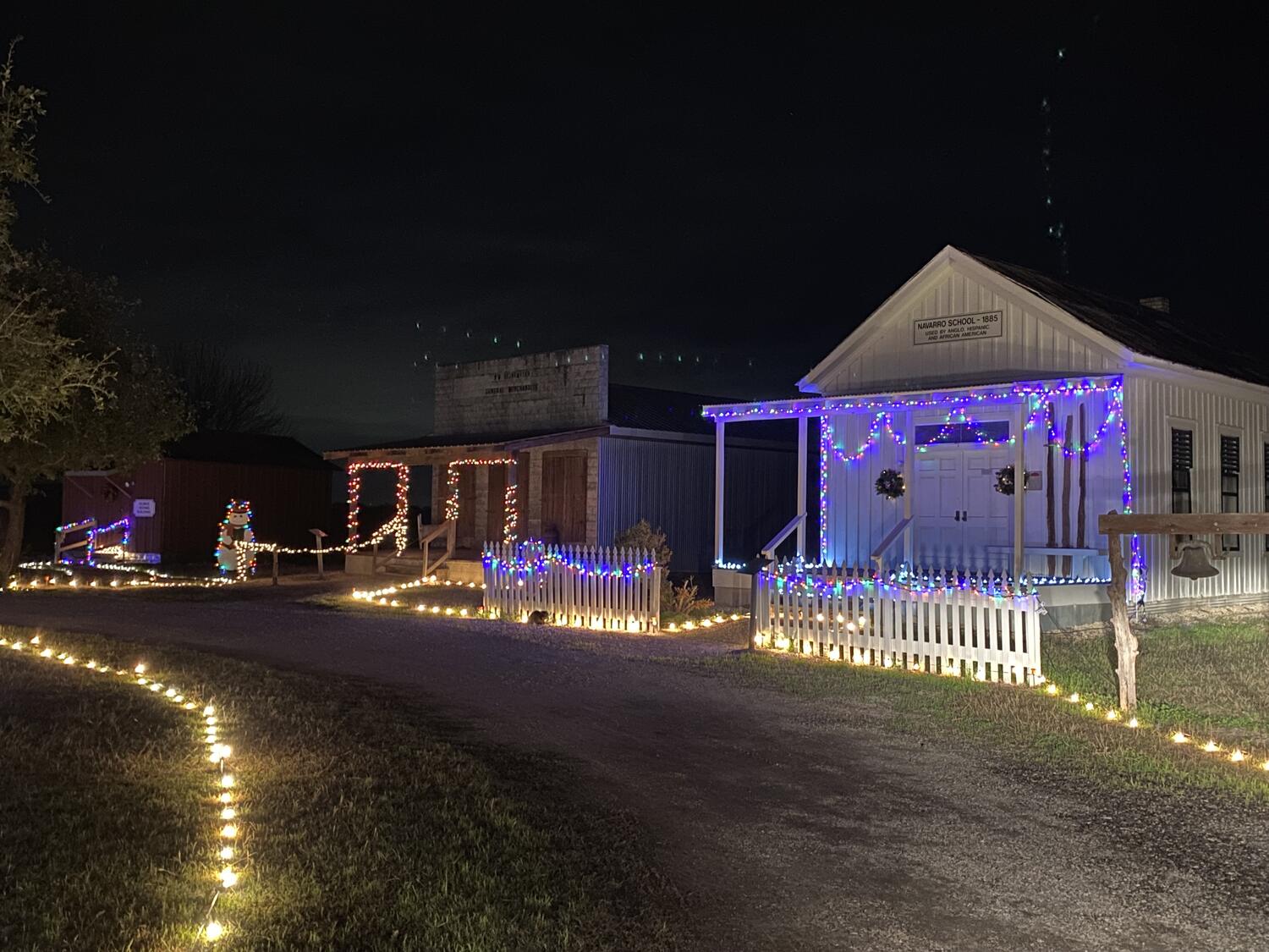 Heritage Village buildings along a lighted path at night