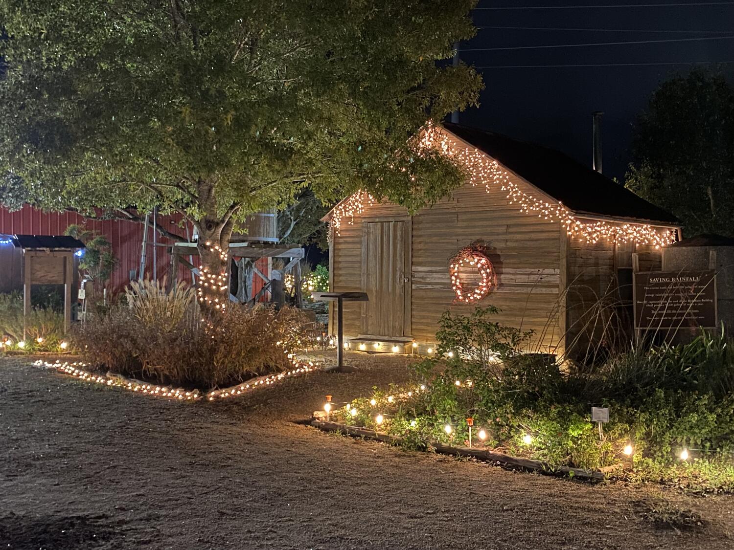 A wooden farm building with a wreath and white Christmas lights